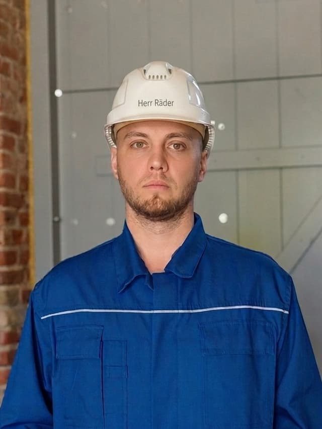 Lukas Räder, Sicherheitsingenieur und Fachkraft für Arbeitssicherheit, mit Schutzhelm und Arbeitskleidung